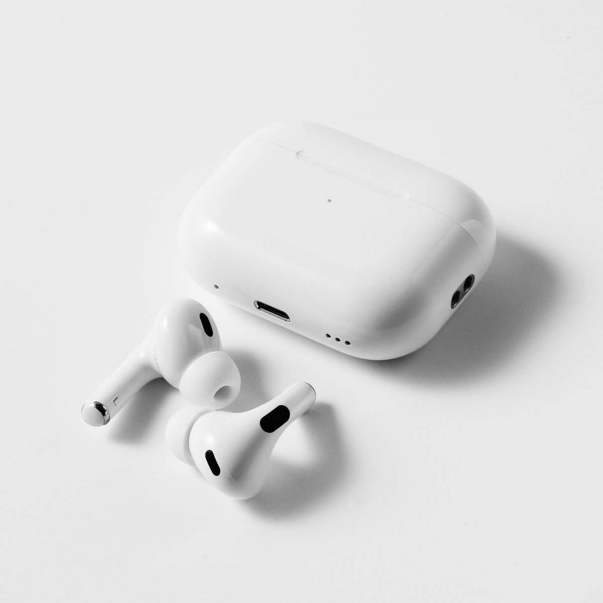 Apple AirPods Pro earbuds next to white charging case